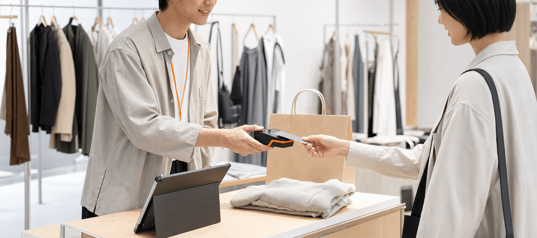 アパレル店内でタブレットレジを使い会計して商品を手渡す様子